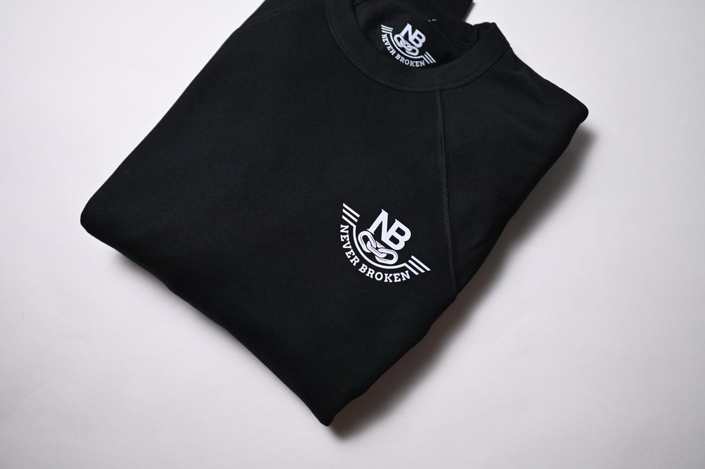 Folded black sweatshirt with 'Never Broken' logo on a white background