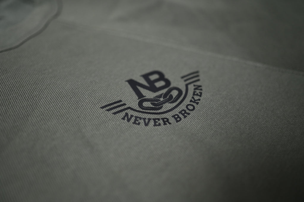 Close-up of a gray fabric with 'Never Broken' logo embroidered on it.