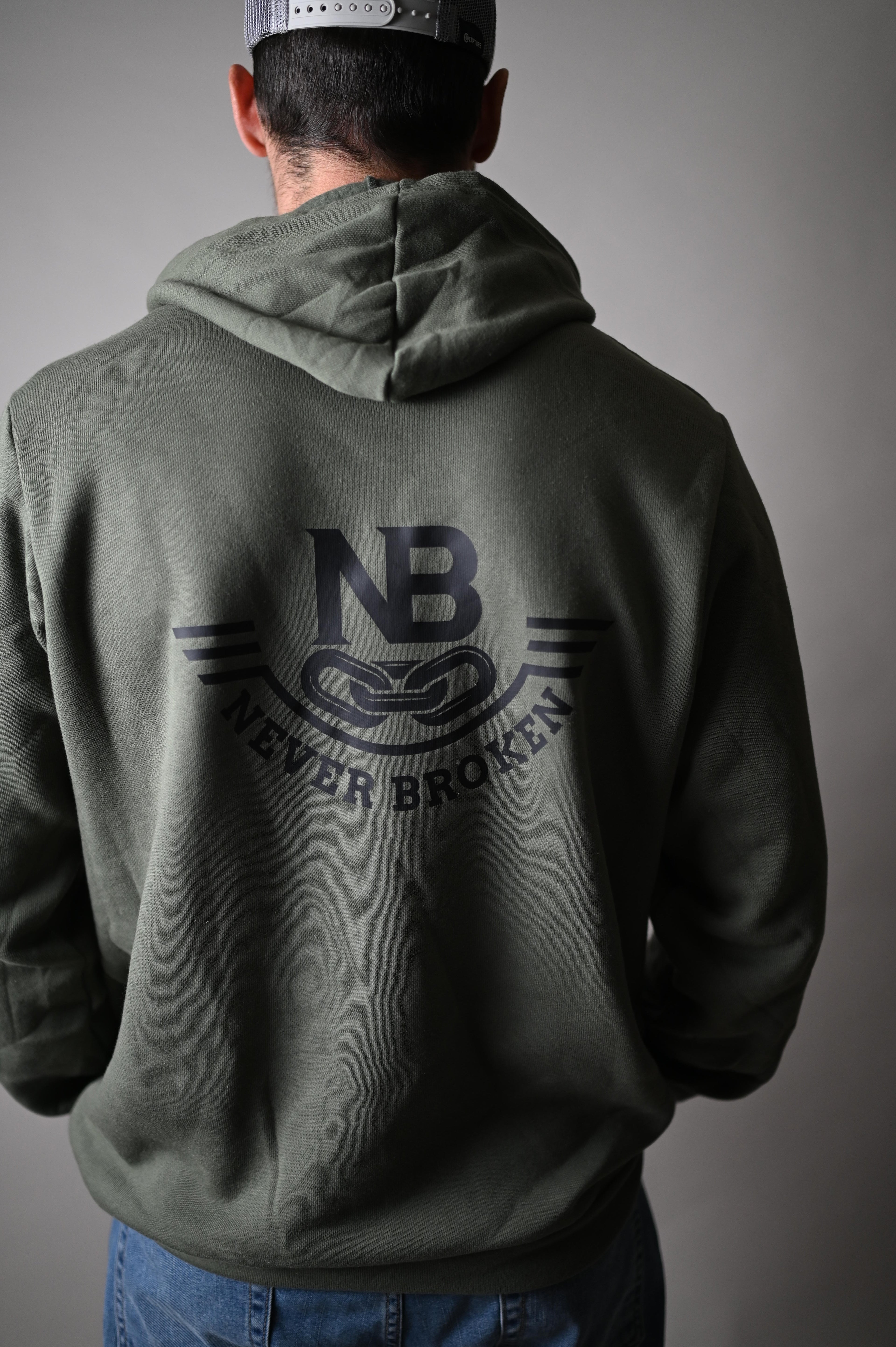 Person wearing a green hoodie with a logo on a gray background