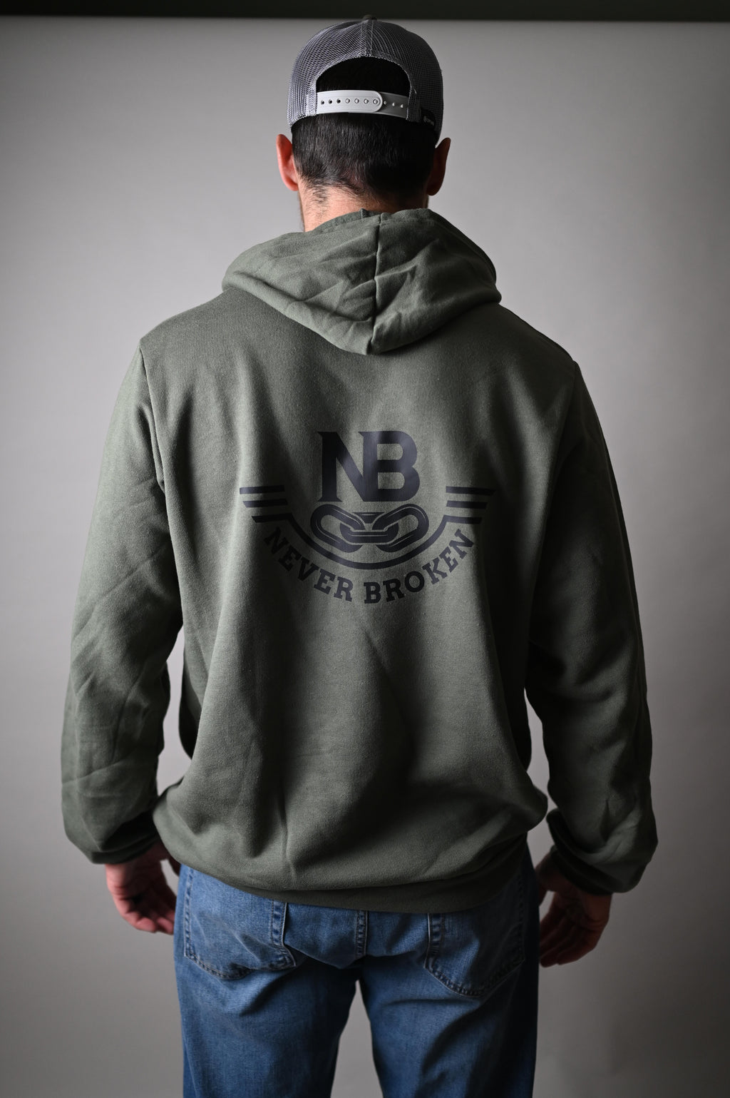 Person wearing a green jacket with a logo on the back against a gray background