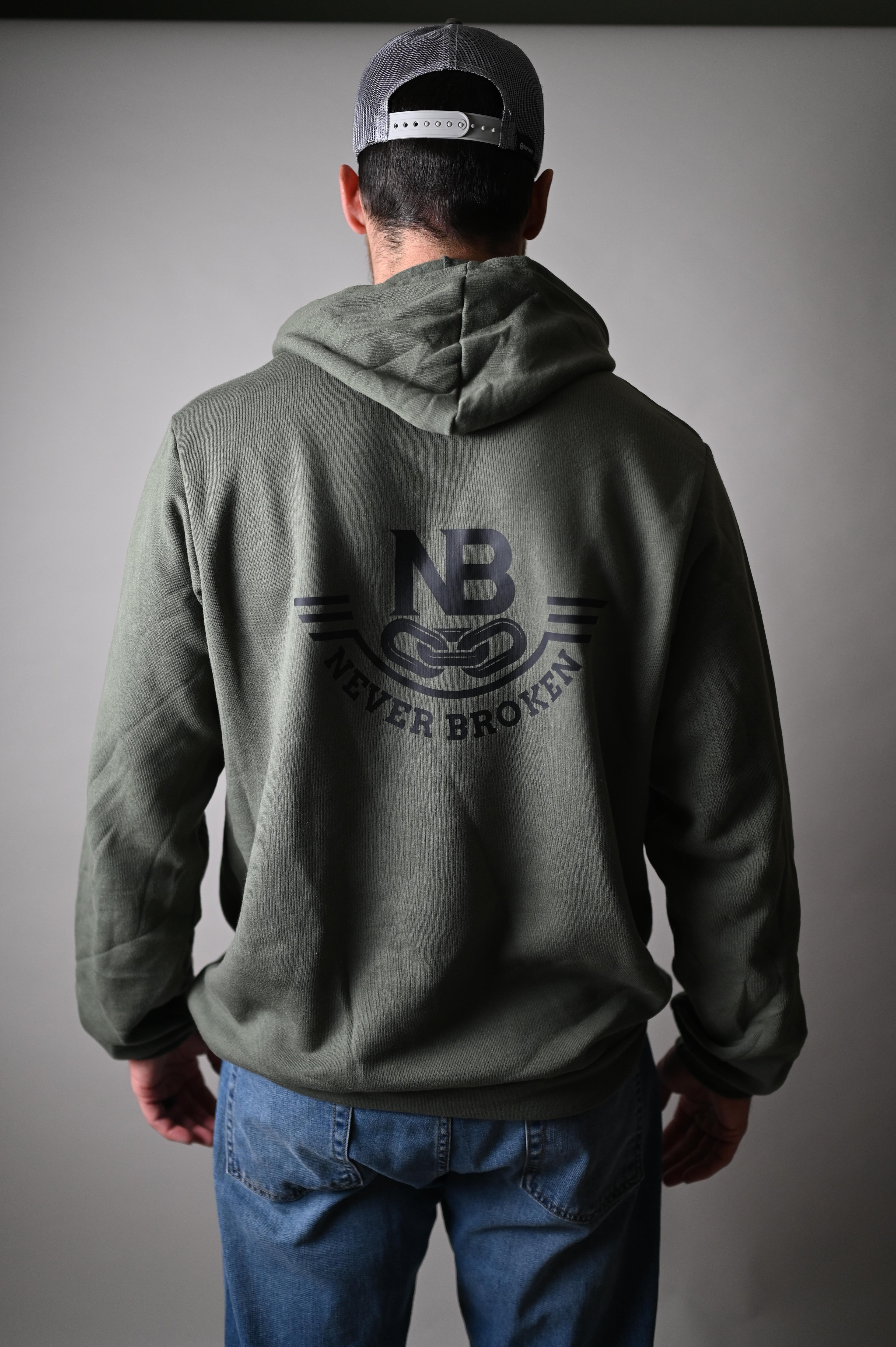 Person wearing a green jacket with a logo on the back against a gray background