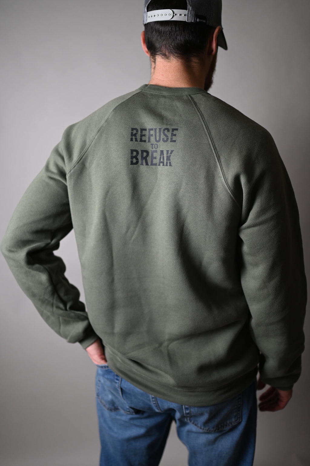 Person wearing a green jacket with text on the back against a gray background