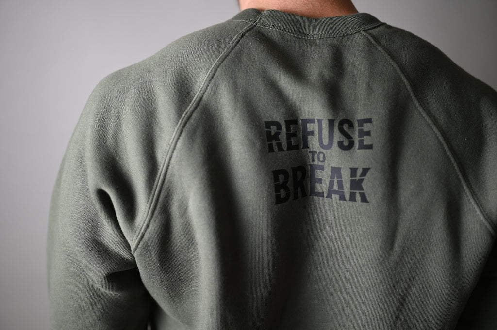 Person wearing a green sweatshirt with 'REFUSE TO BREAK' text on the back against a gray background